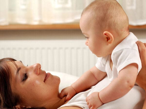 A woman and baby laying in bed together.