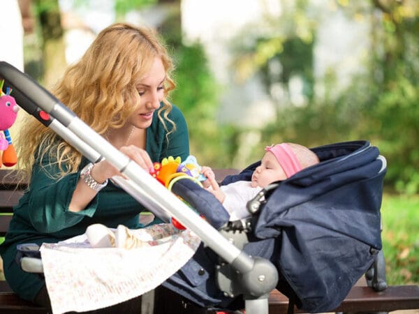 A woman feeding her baby in the stroller.