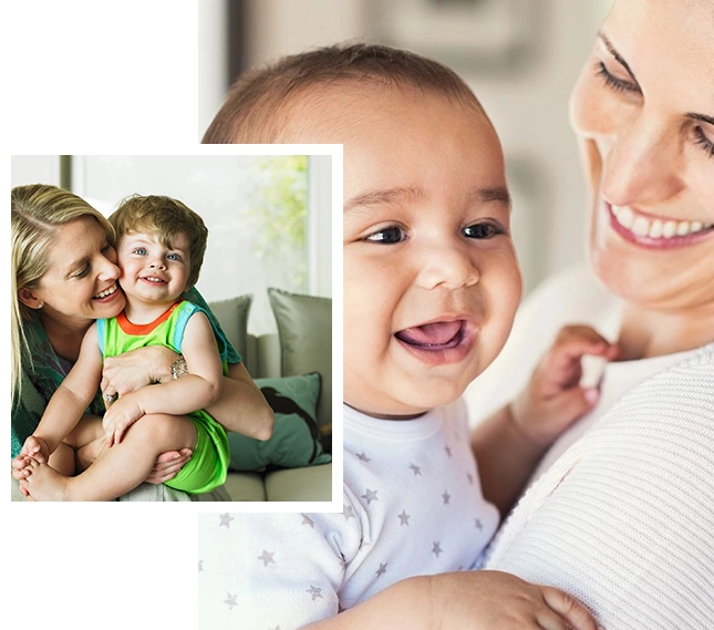 A woman holding a baby and smiling at the camera.