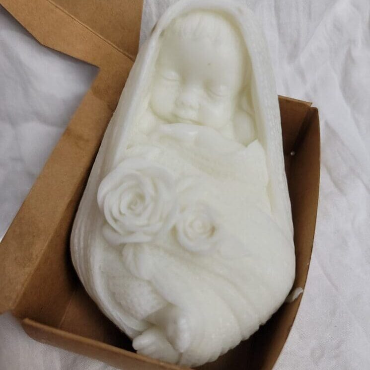 A white baby shoe with roses in it.